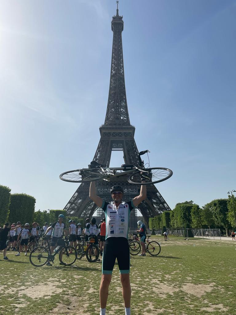 Cyclist with bike overhead at Eiffel Tower